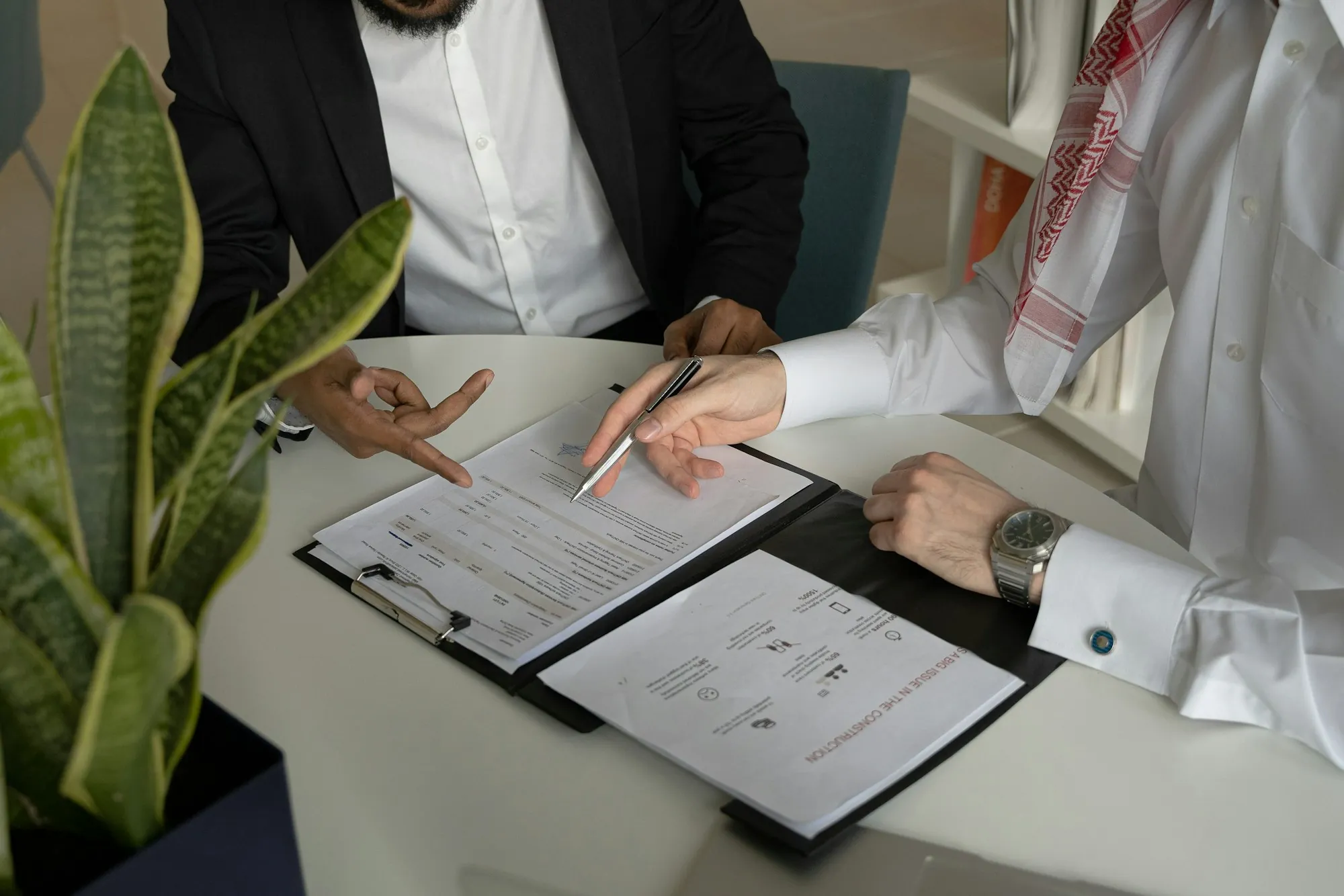 Pen pointing to a form on a clipboard during a meeting