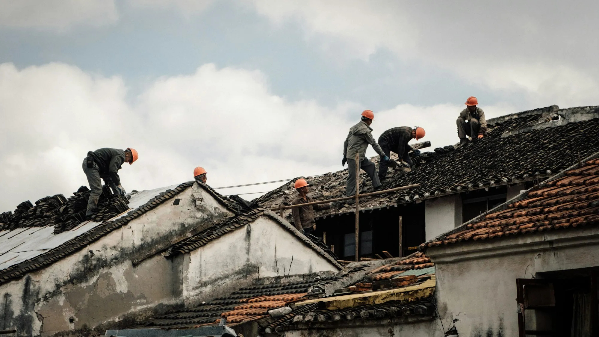 Team of roofers stripping and repairing an old roof
